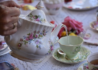 person holding white ceramic teapot