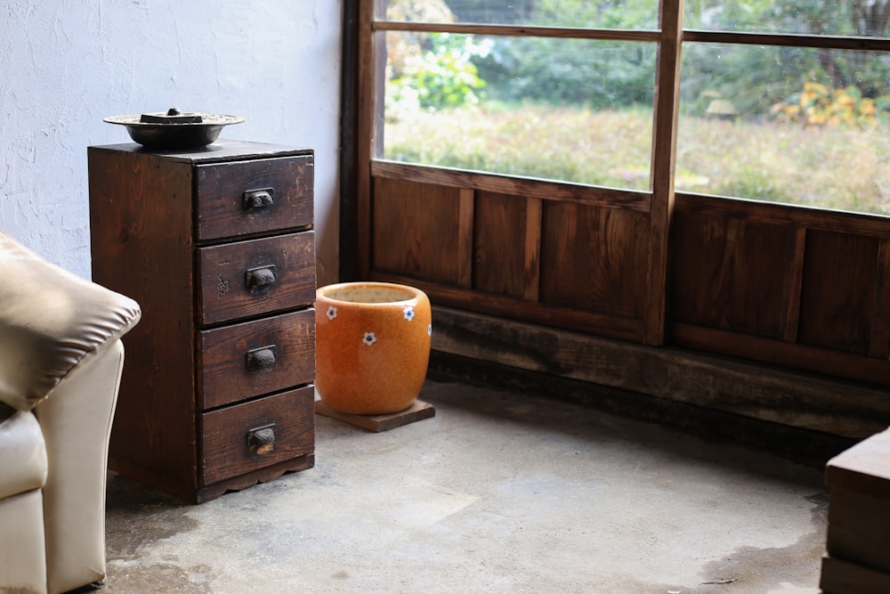 vaso de chão laranja ao lado da cômoda de madeira marrom