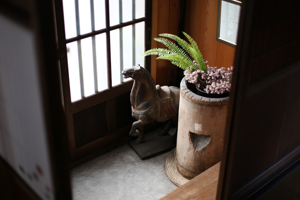 horse figurine beside flowers in pot