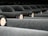 Several rows of dusty wine bottles are stored horizontally, their corks facing outwards. The bottles are arranged neatly in a dimly lit environment, suggesting a wine cellar or storage area.