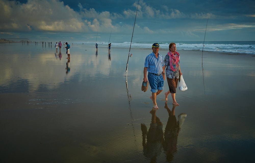 Zwei Mann und Frau gehen am Meeresufer spazieren