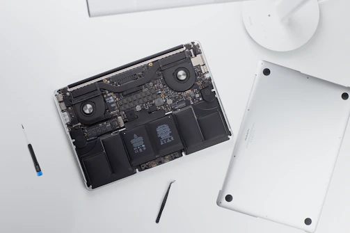 An open MacBook showing a replaced keyboard part, with tools neatly arranged nearby.