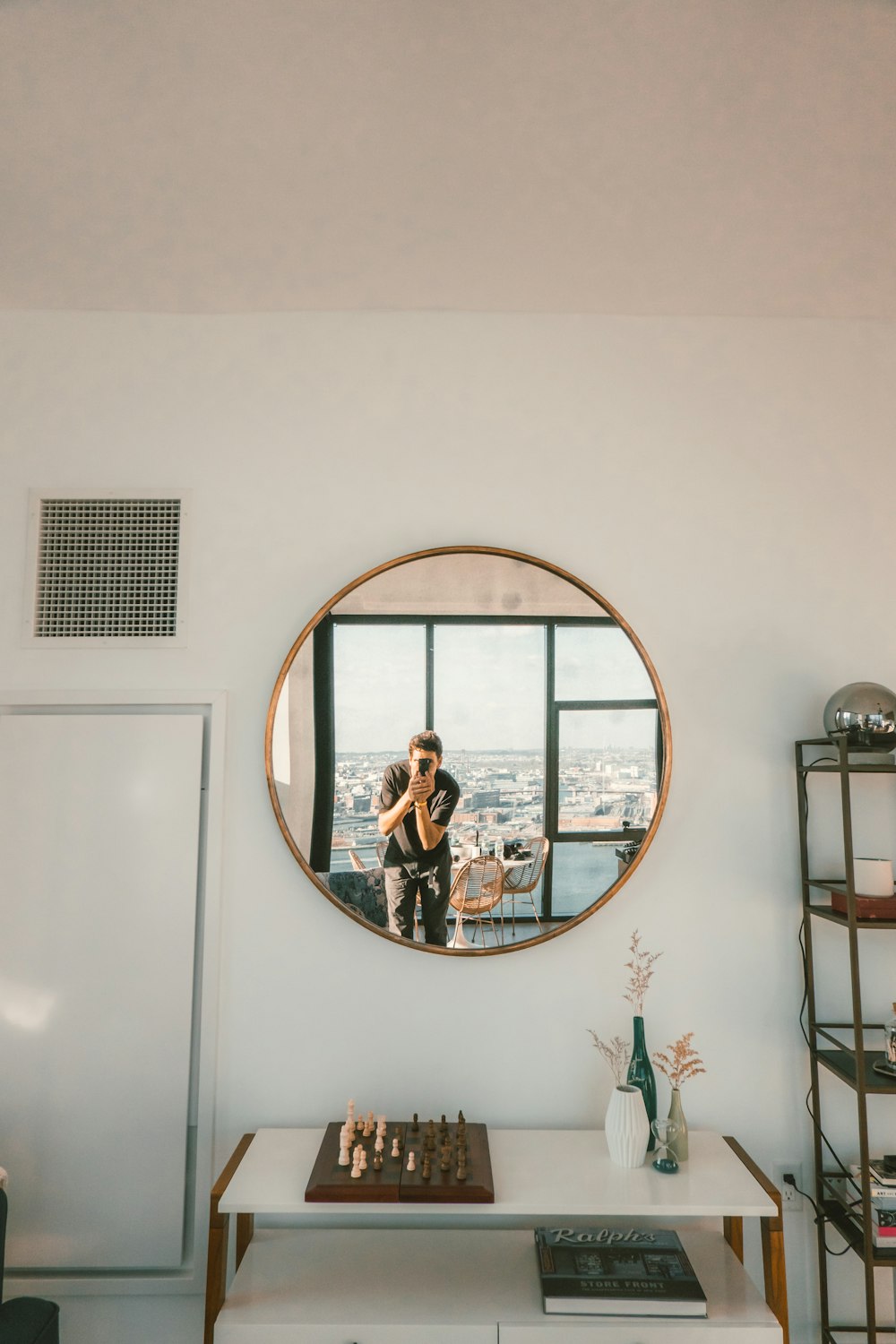 person taking photo of round wall mirror during daytime