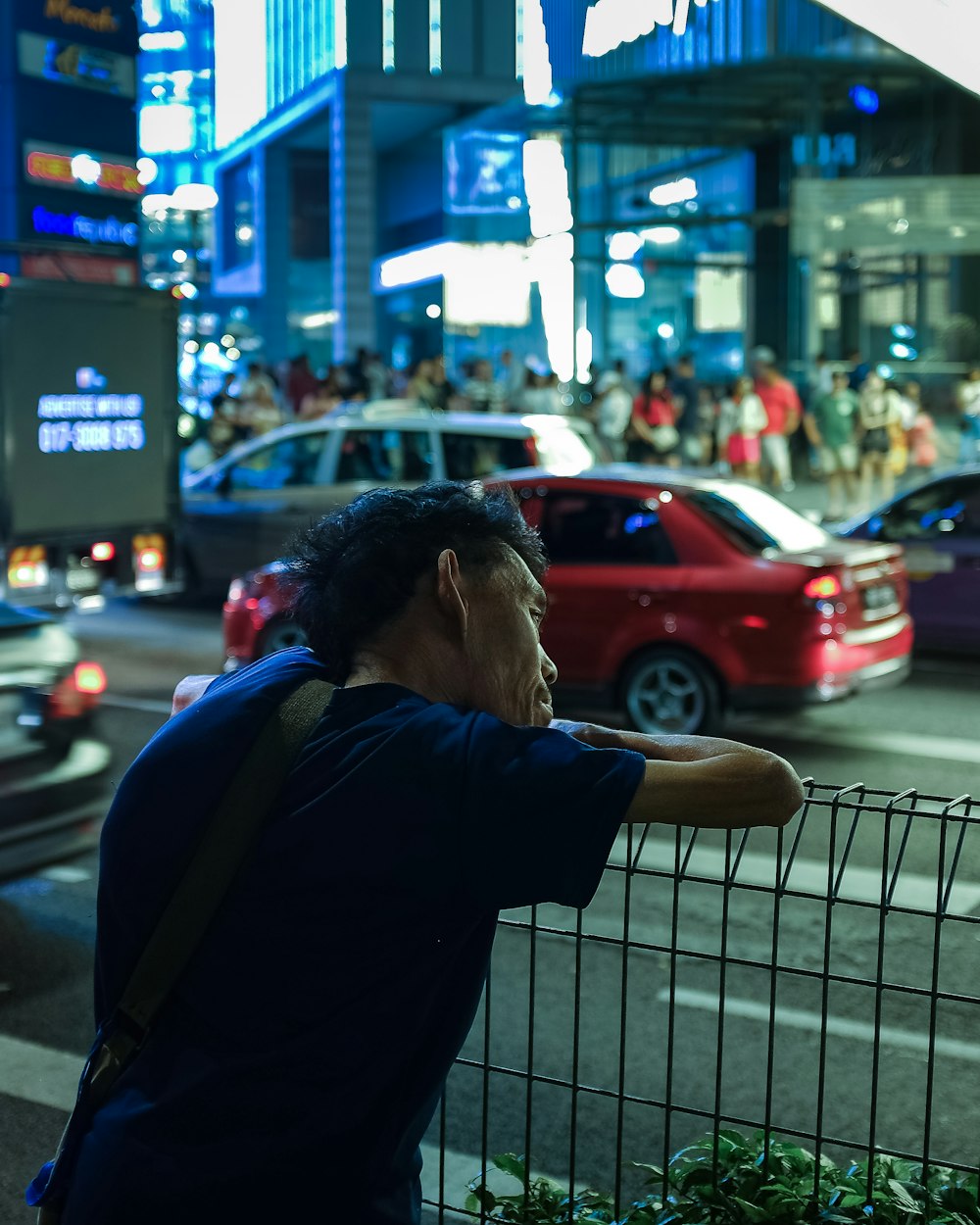 man in blue shirt leaning on fence