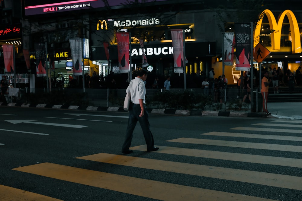 man in white shirt walking on pedestrian lane