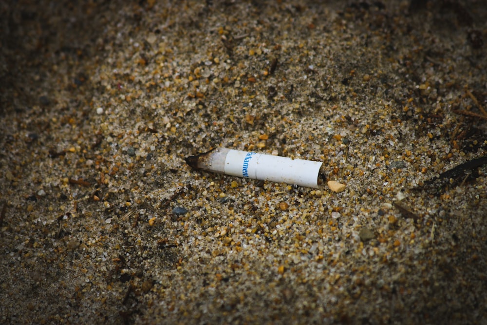 bituca de cigarro branca na areia marrom