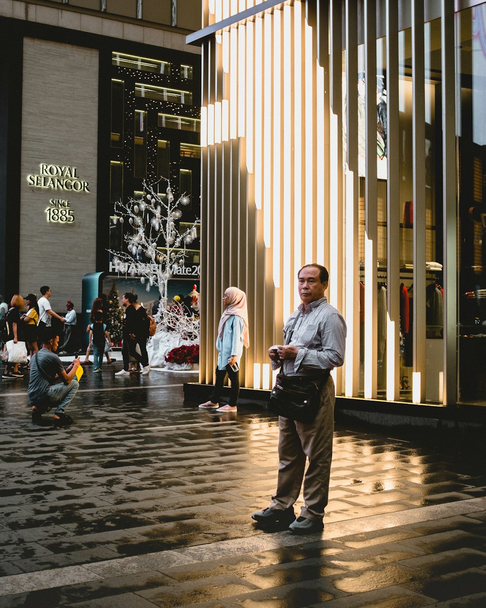 man in grey dress shirt and beige pants near people walking