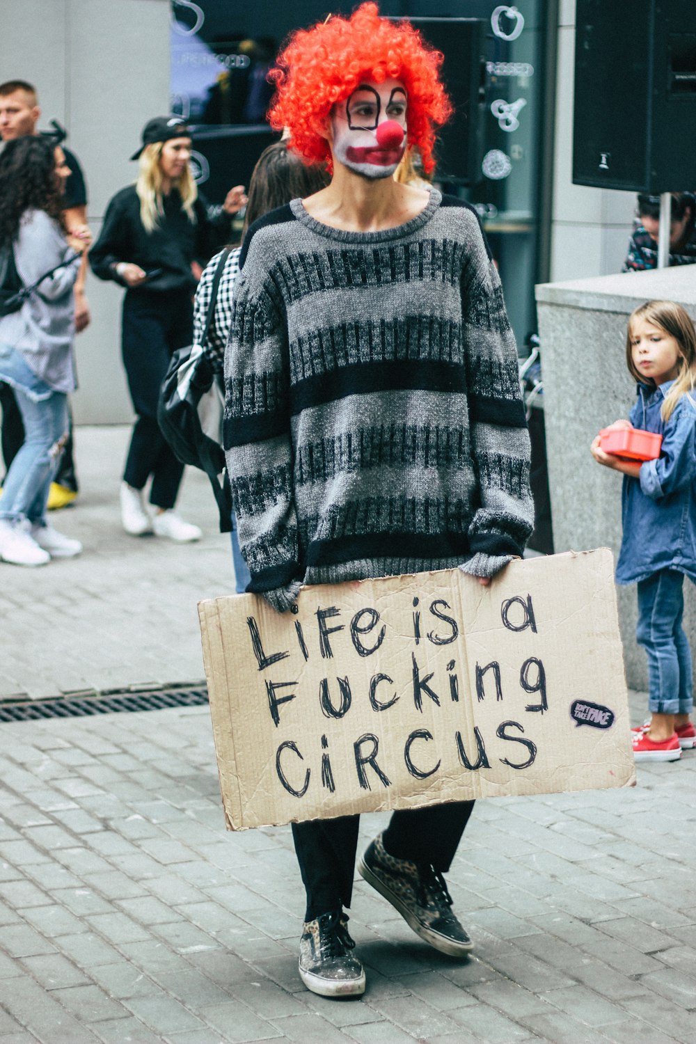 man in grey and black striped sweater holding signage