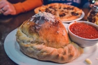 A close-up of a calzone, golden and stuffed with cheese.