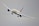 A commercial airplane is flying at a slight bank in a clear sky. The aircraft has a sleek design with long wings and powerful jet engines, positioned below each wing.