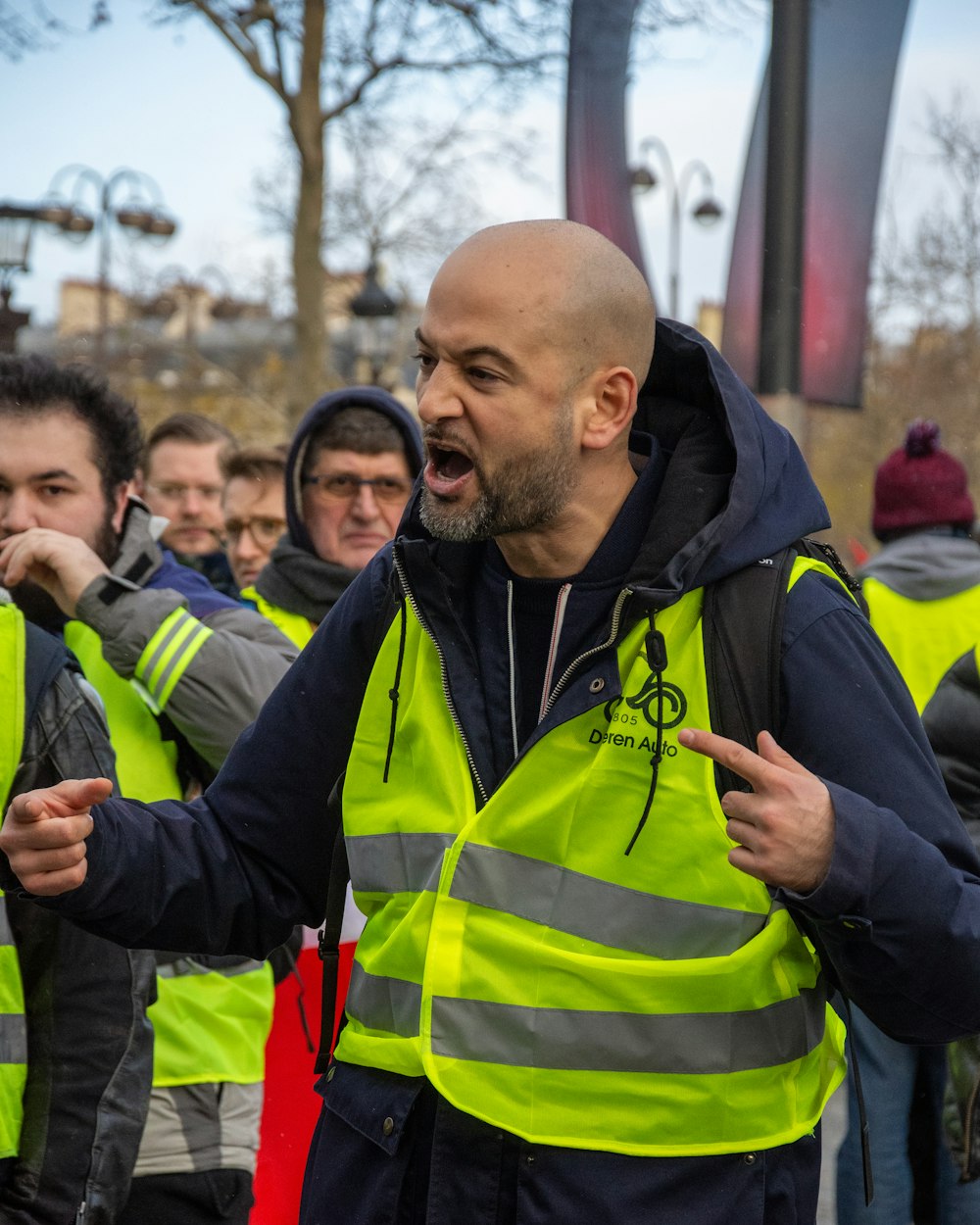 man standing while wearing black zip-up hoodie and green safety vest