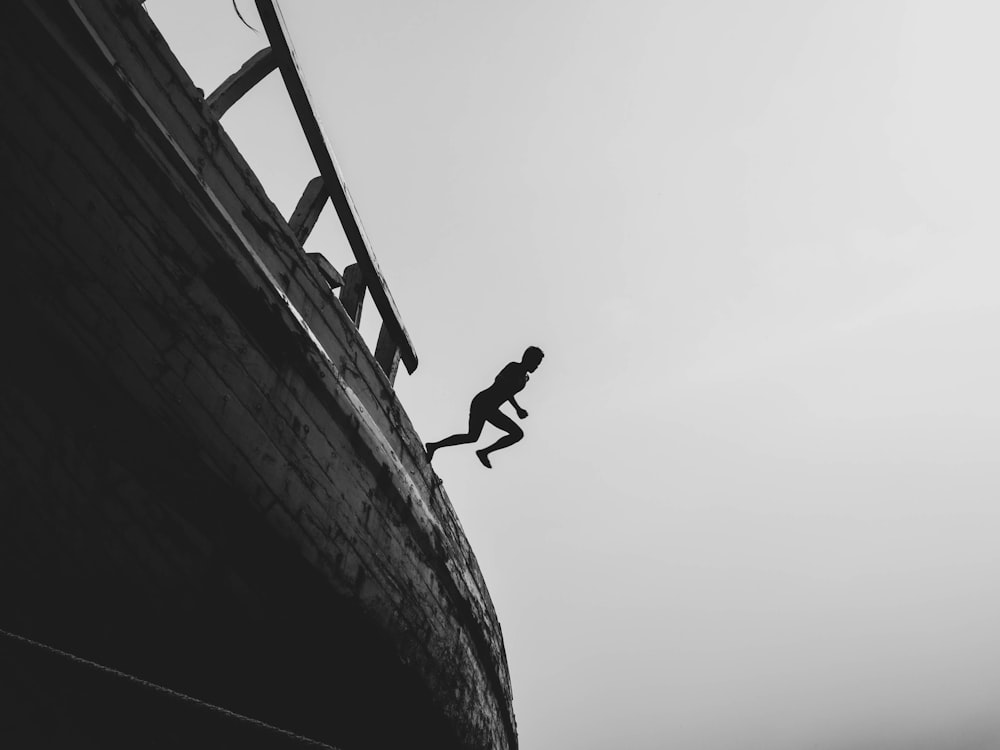 silhouette photography of person jumping on sailing ship