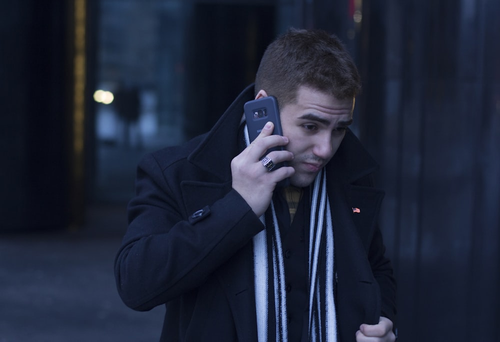 man holding smartphone wearing black suit jacket