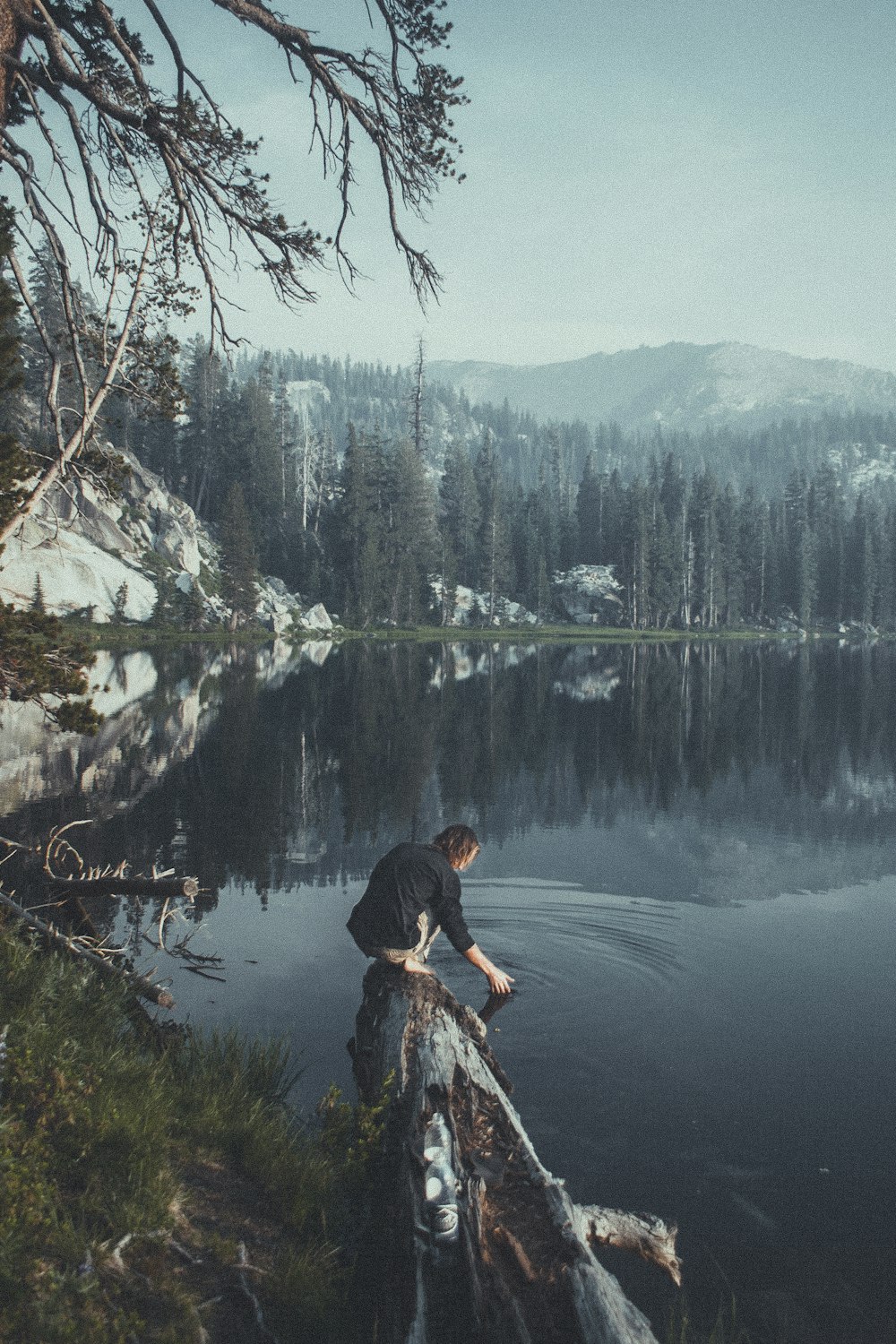 man on wood log beside water