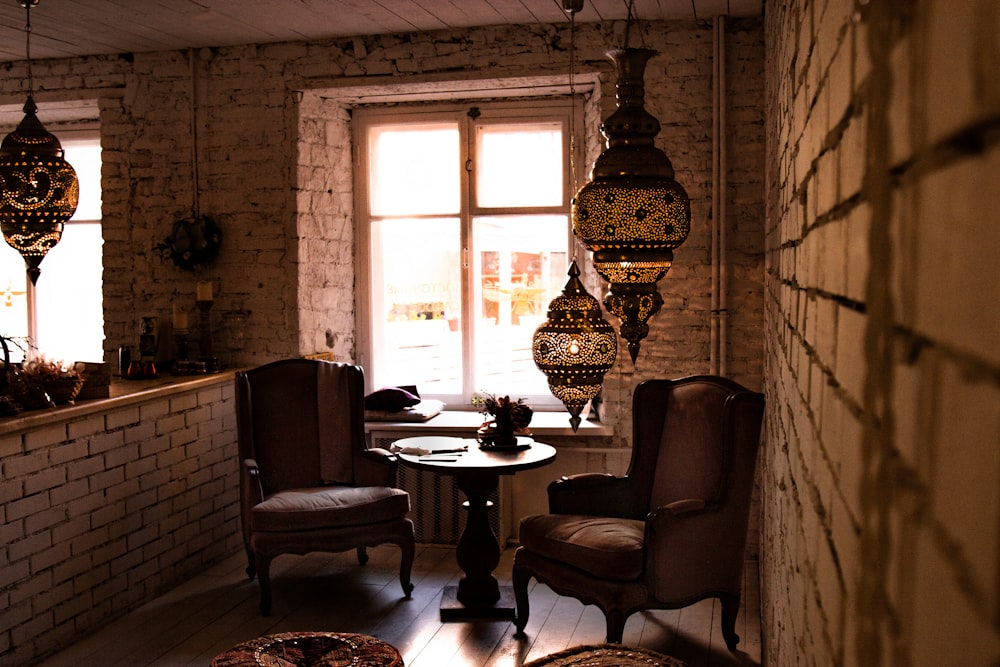 round brown wooden table between of wing armchairs indoors