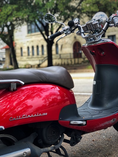 A sleek red automatic scooter parked on a city street in Indonesia.