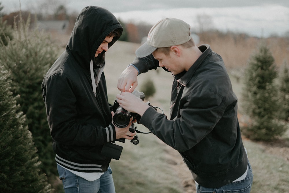 man fixing DSLR camera while man holding