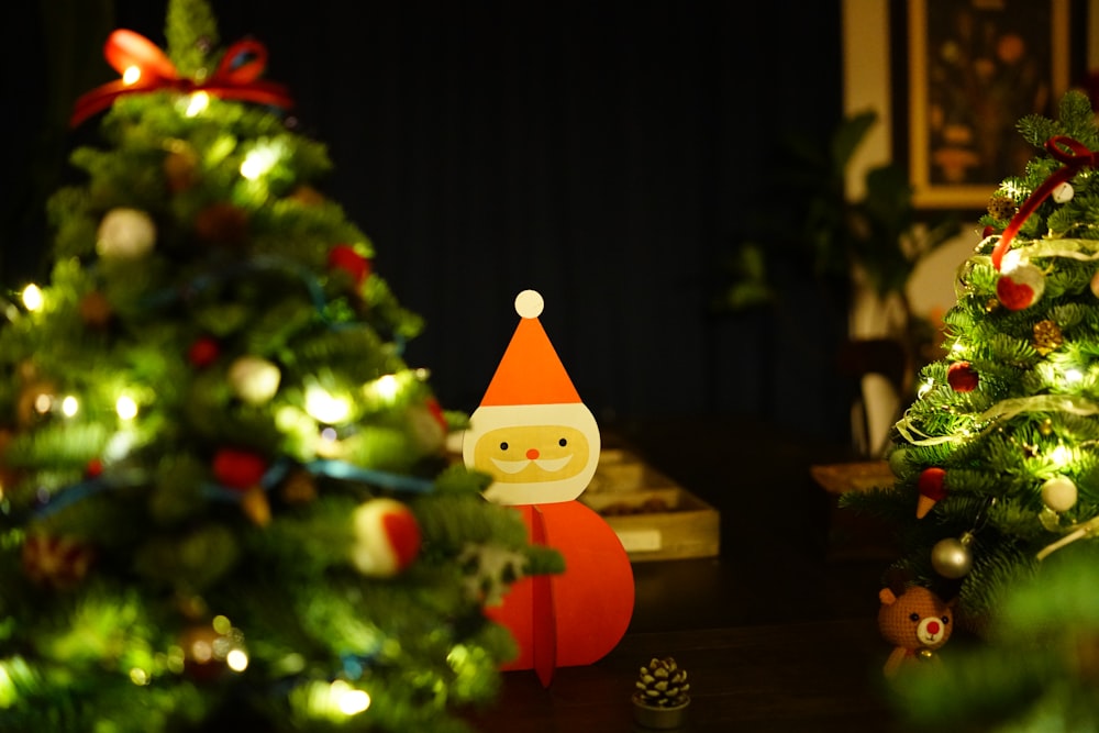 Santa Claus figurine in between Christmas trees