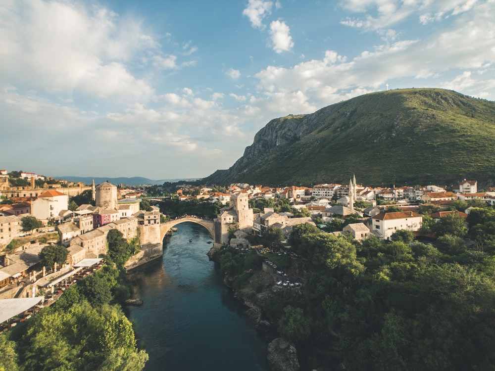 Puente de arco marrón cerca de edificios de concreto y árboles de hojas verdes durante el día