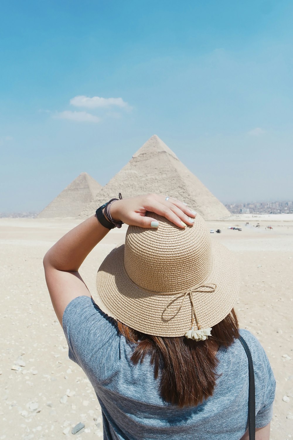 femme en haut bleu debout devant la pyramide pendant la journée