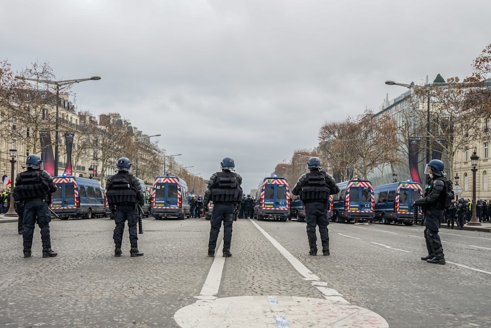 five police standing on street in front vehicles during daytime
