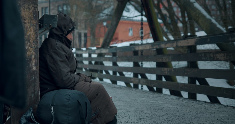 person in jacket sitting on green bag outdoors