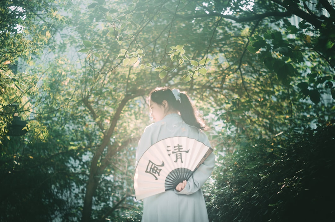 woman in grey robe holding hand fan