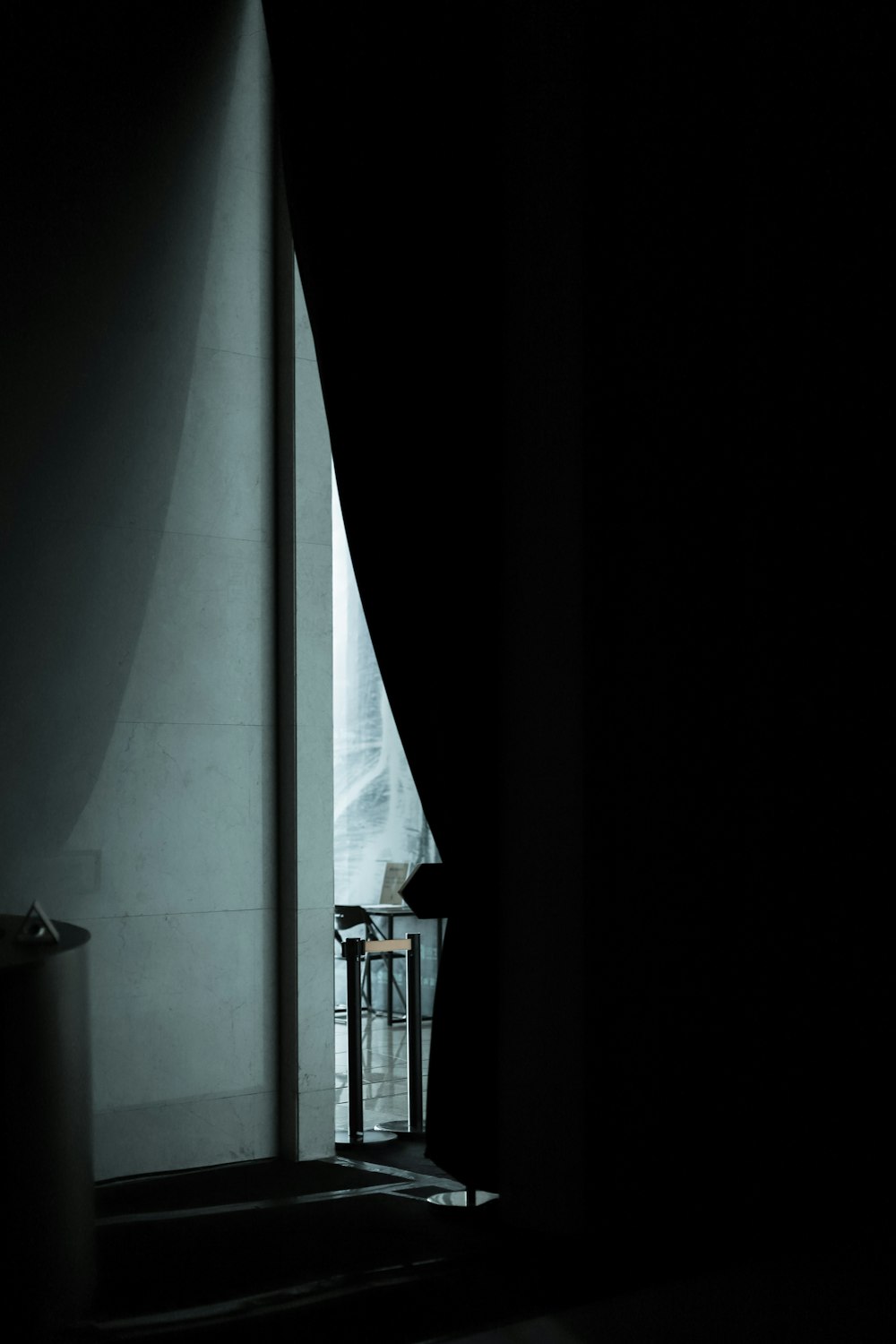 uma pessoa em pé em um quarto escuro ao lado de uma janela