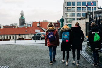 four persons walking on concrete road during daytime