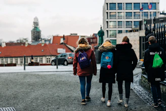 four persons walking on concrete road during daytime
