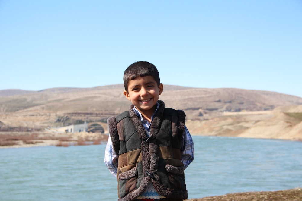 boy standing in front of body of water