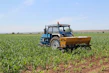 A modern agricultural machine working in a lush green field under a clear sky.