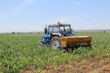 A sturdy tractor working in a lush green field under clear skies.