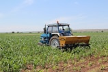 Modern agricultural machinery working in a vast field under blue sky.