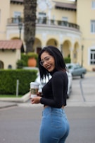 A smiling customer holding a steaming cup of coffee outside our shop.