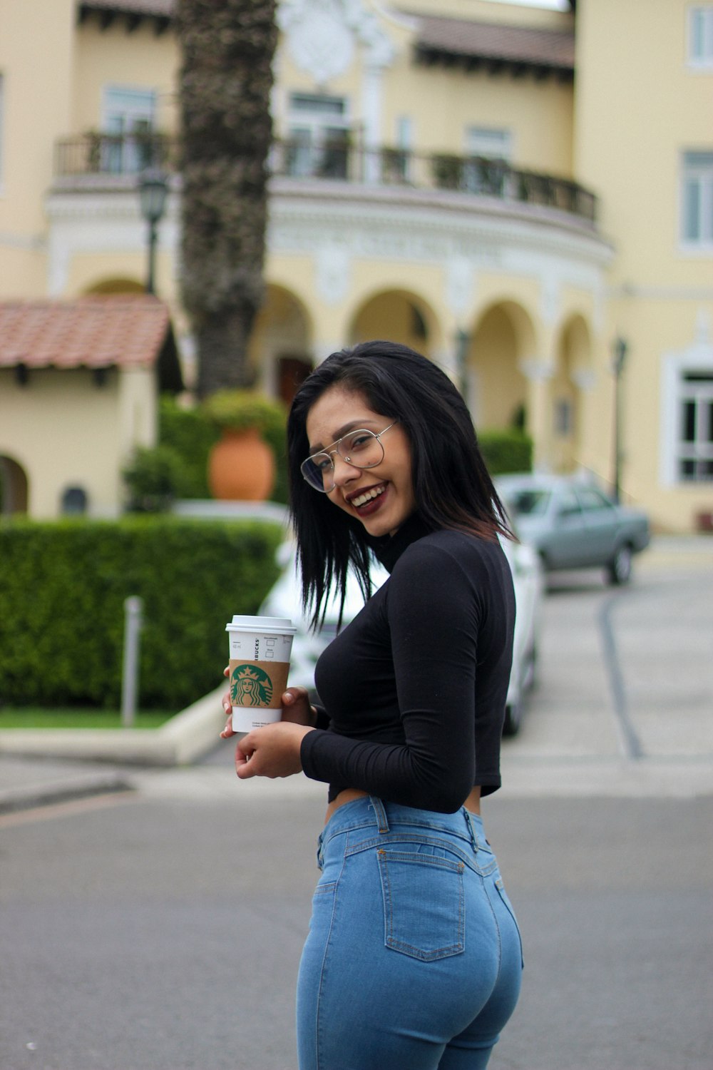 smiling woman holding Starbucks disposable cup