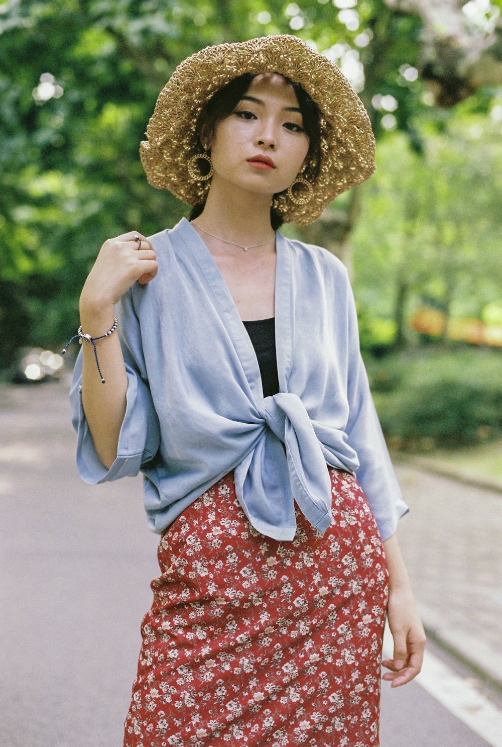 standing woman wearing blue cardigan and red skirt