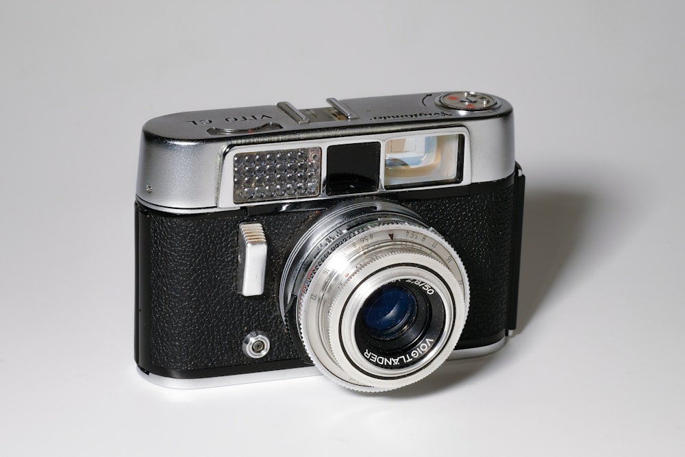 gray and black point-and-shoot camera on white surface
