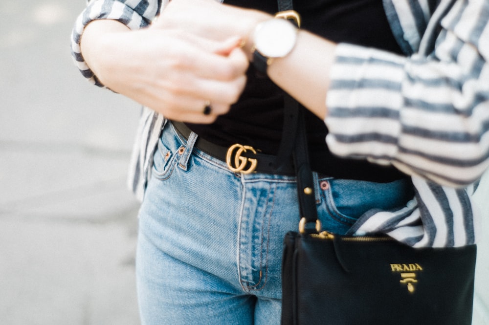 woman wearing cardigan and denim bottoms looking at the time on her watch