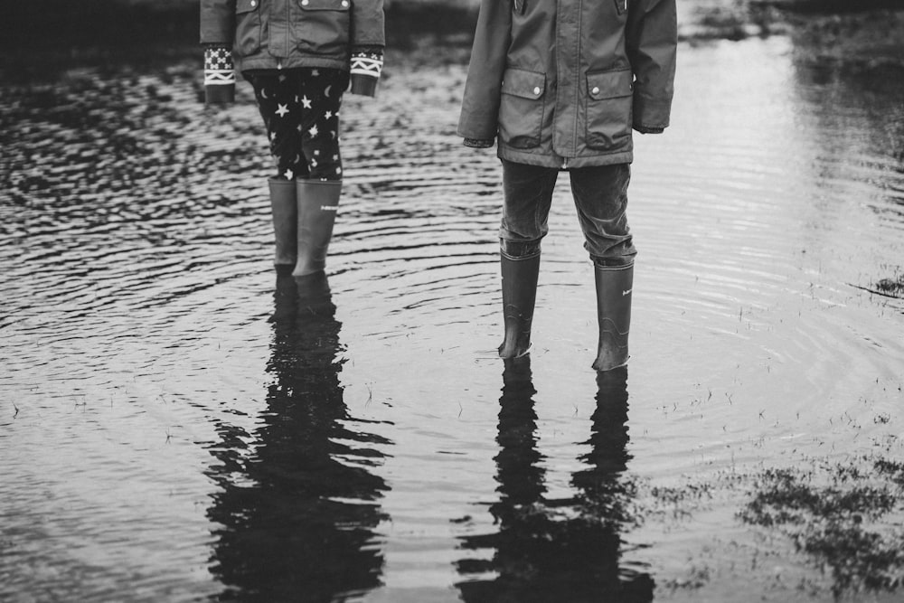 grayscale photo of person standing on body of water