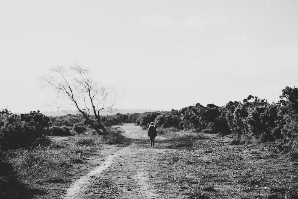 person walking middle of empty space grayscale photo