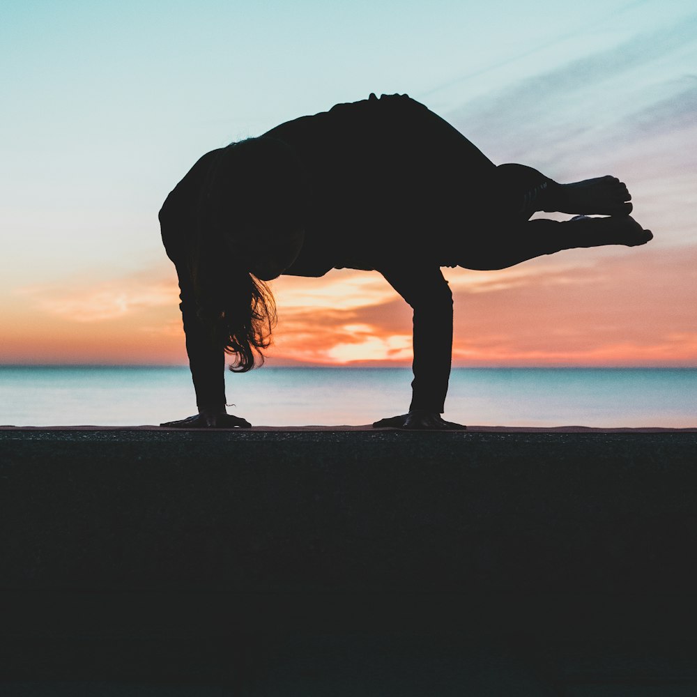 silhouette of person doing hand stand