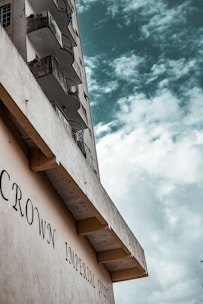 A tall building with balconies, viewed from below with an overcast sky in the background. The structure displays the words 'CROWN IMPERIAL COURT' on its facade.