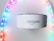 A white Amazon device, possibly a smart speaker, is positioned in the center with a soft focus on colorful LED strip lights forming an arch around it. The LED lights display a gradient of colors including purple, pink, blue, and green.