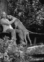 Andre smiling warmly while sitting on a park bench with a relaxed dog beside him.