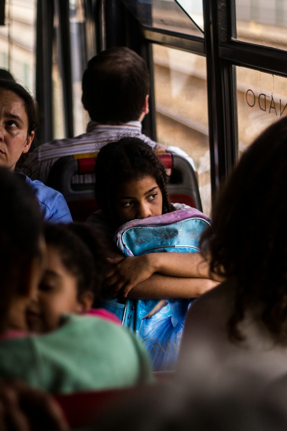 girl with blue bag inside bus