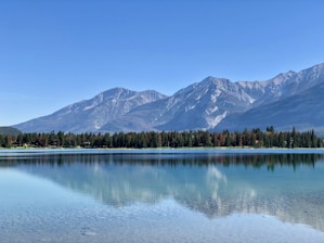 A serene landscape with a tranquil lake reflecting mountains under a clear sky.