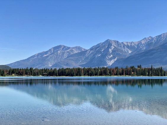 A serene landscape with a tranquil lake reflecting mountains under a clear sky.