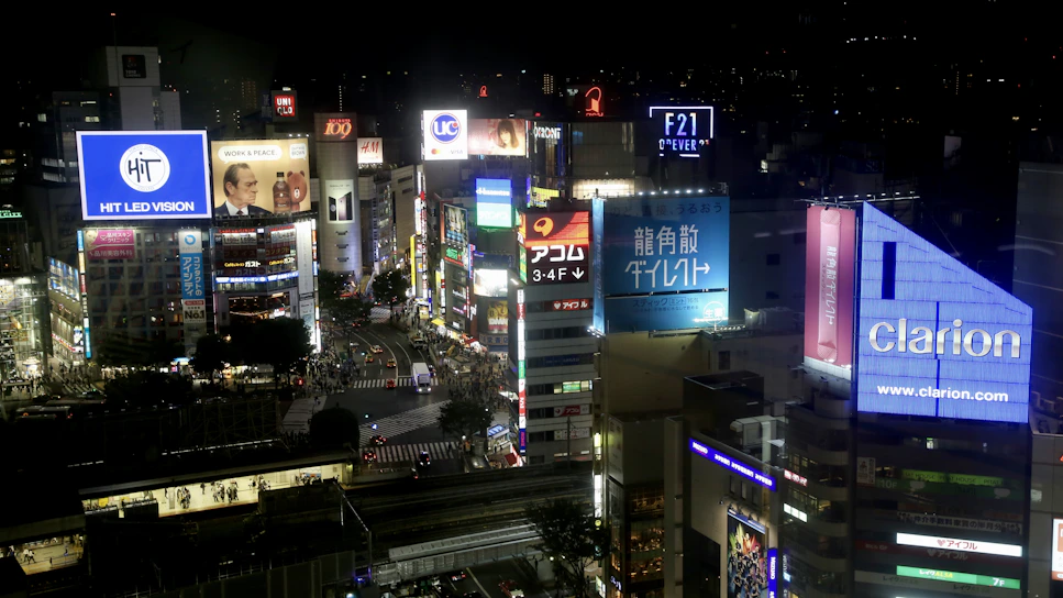 A vibrant cityscape at dusk showcasing multiple digital rental out-of-home billboards glowing brightly.