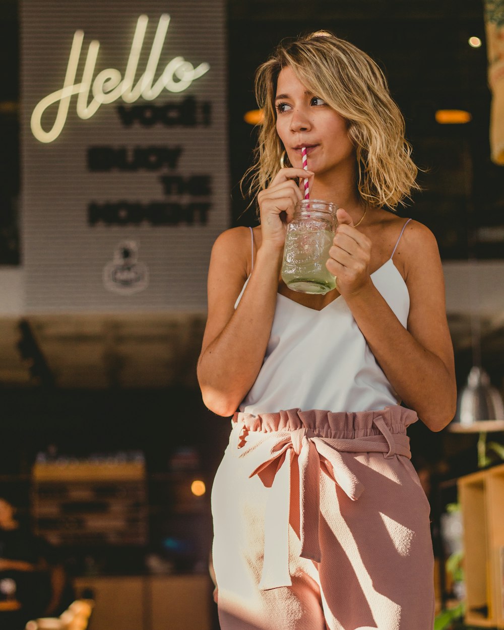 woman drinking mint juice standing beside building